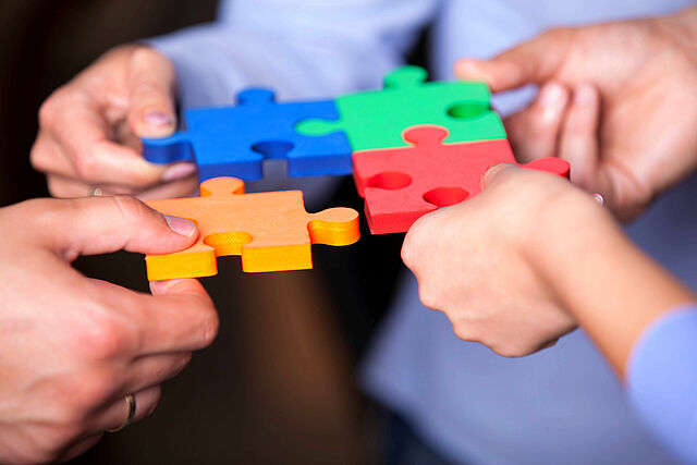 Auf dem Bild sind bunte Puzzelteile. 